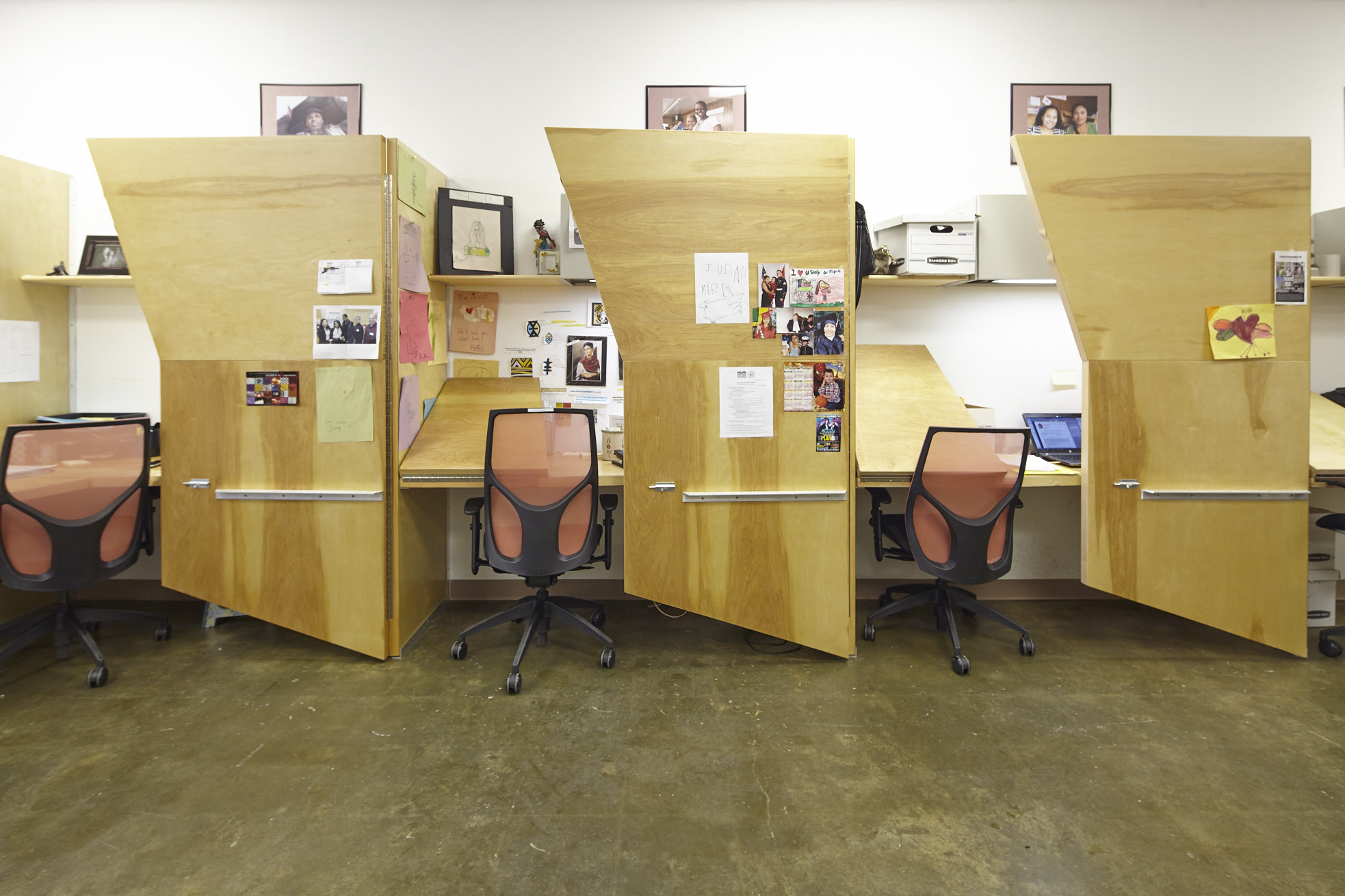 Three natural wood, asymmetric cubicles and orange office chairs in the BCS Coney Island Office.