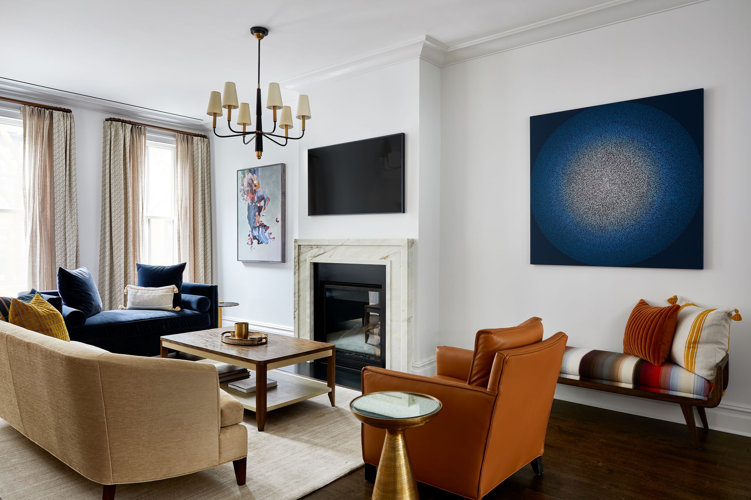 Living room with modern furnishings, including mismatched couches and armchairs and a marble fireplace