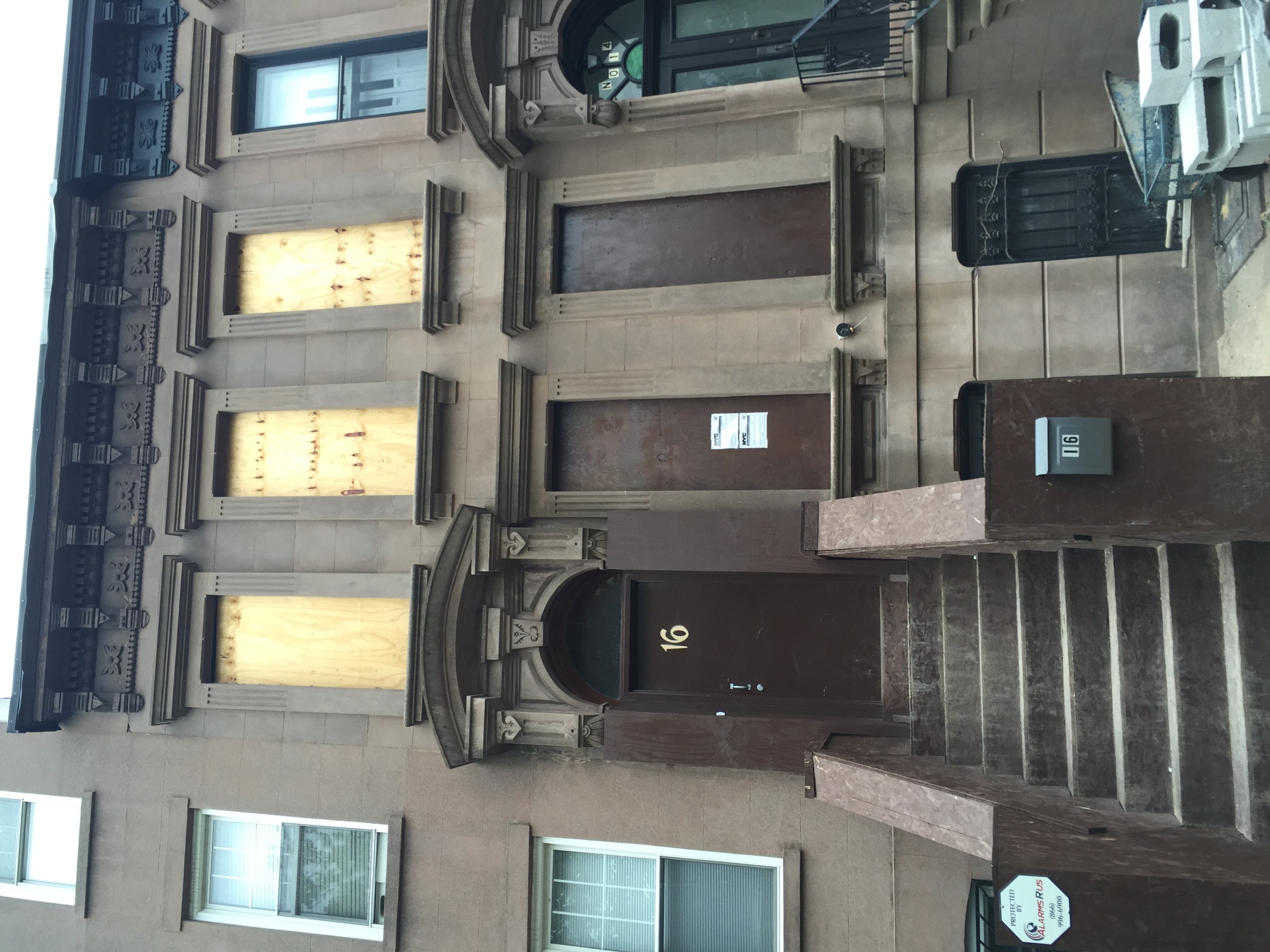 Front facade of a townhouse during construction with all windows boarded up with plywood