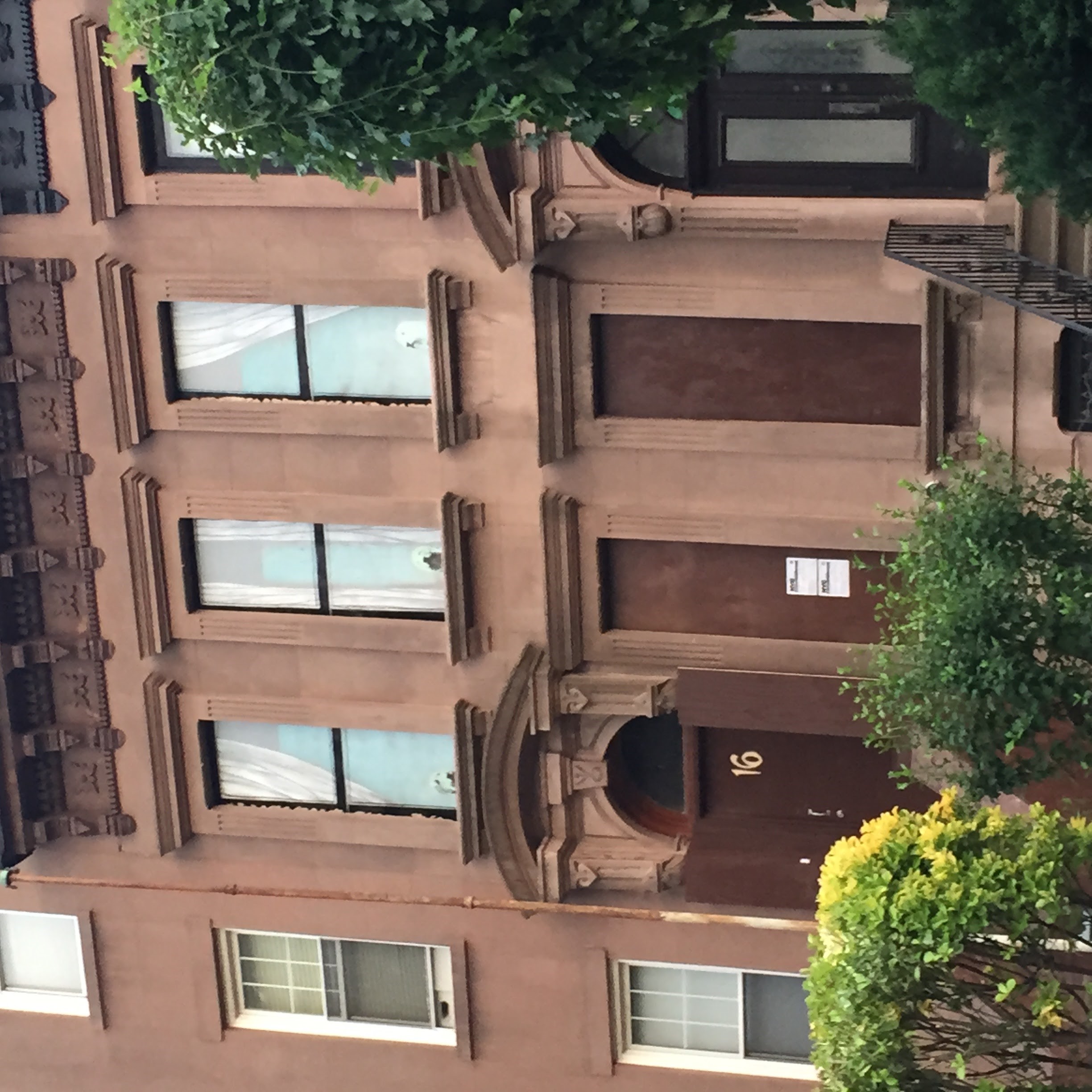 Front facade of a Carroll Gardens home during construction, with curtains and fake windows painted on the boards covering the windows.