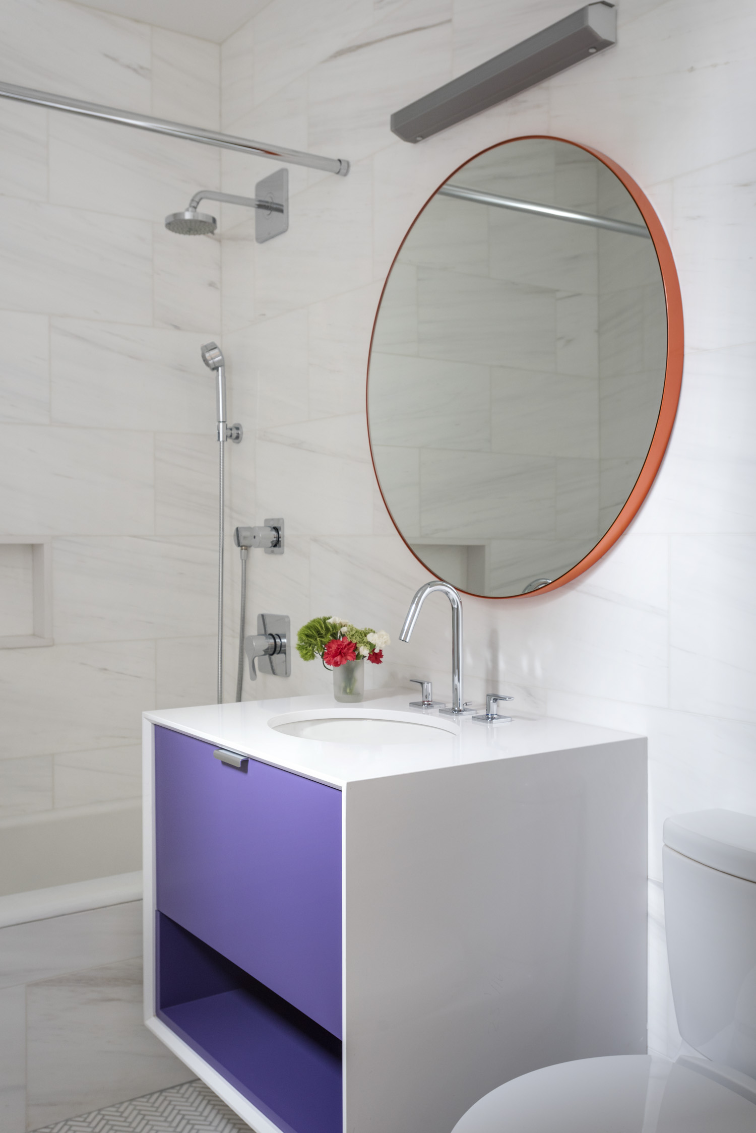 Floating vanity in an all-white bathroom with purple drawers
