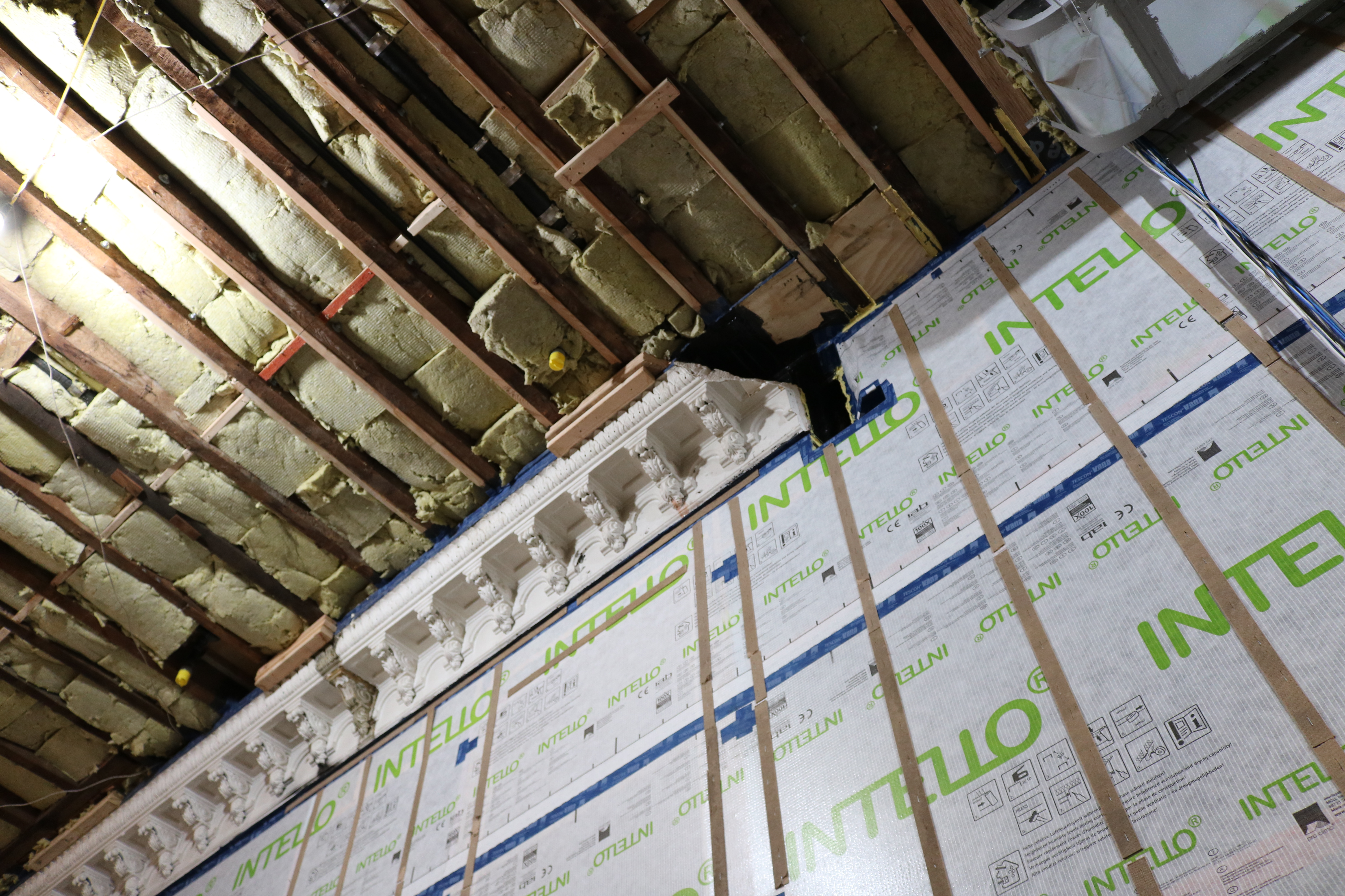 Construction photo showing the preservation process of plaster crown molding during a Passive House retrofit.