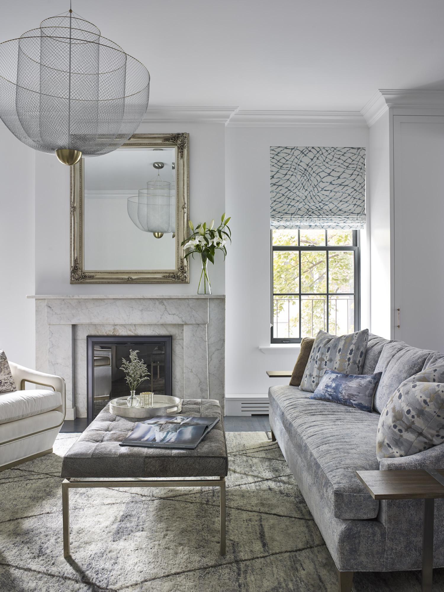 Living room with a textured couch and carpet, mesh chandelier, and marble fireplace