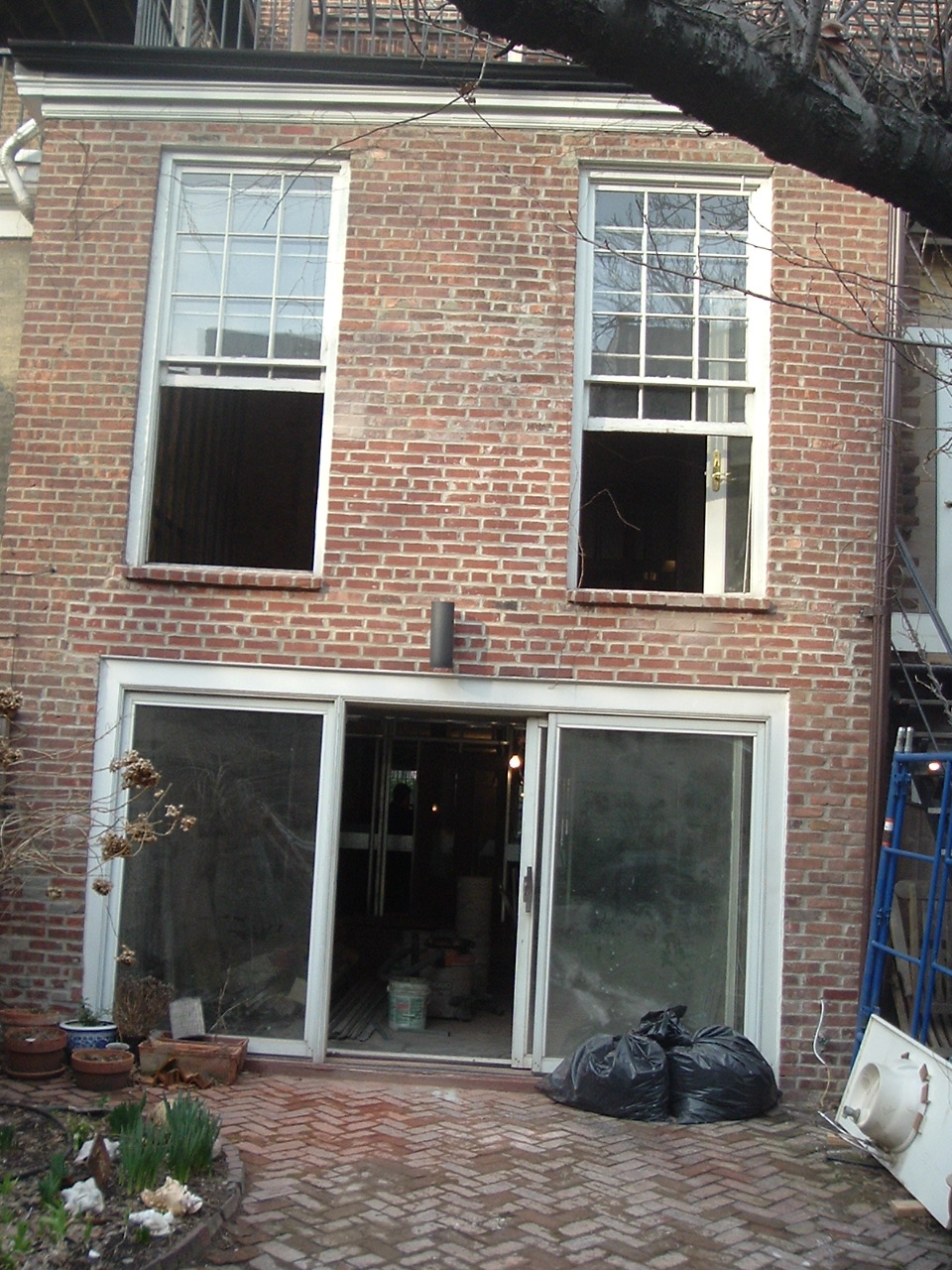 Brick rear façade of a Brooklyn Heights townhouse with brick pavers and sliding glass doors.