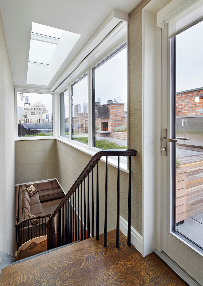 Interior of a bulkhead with a skylight, glass door, and large glass windows.
