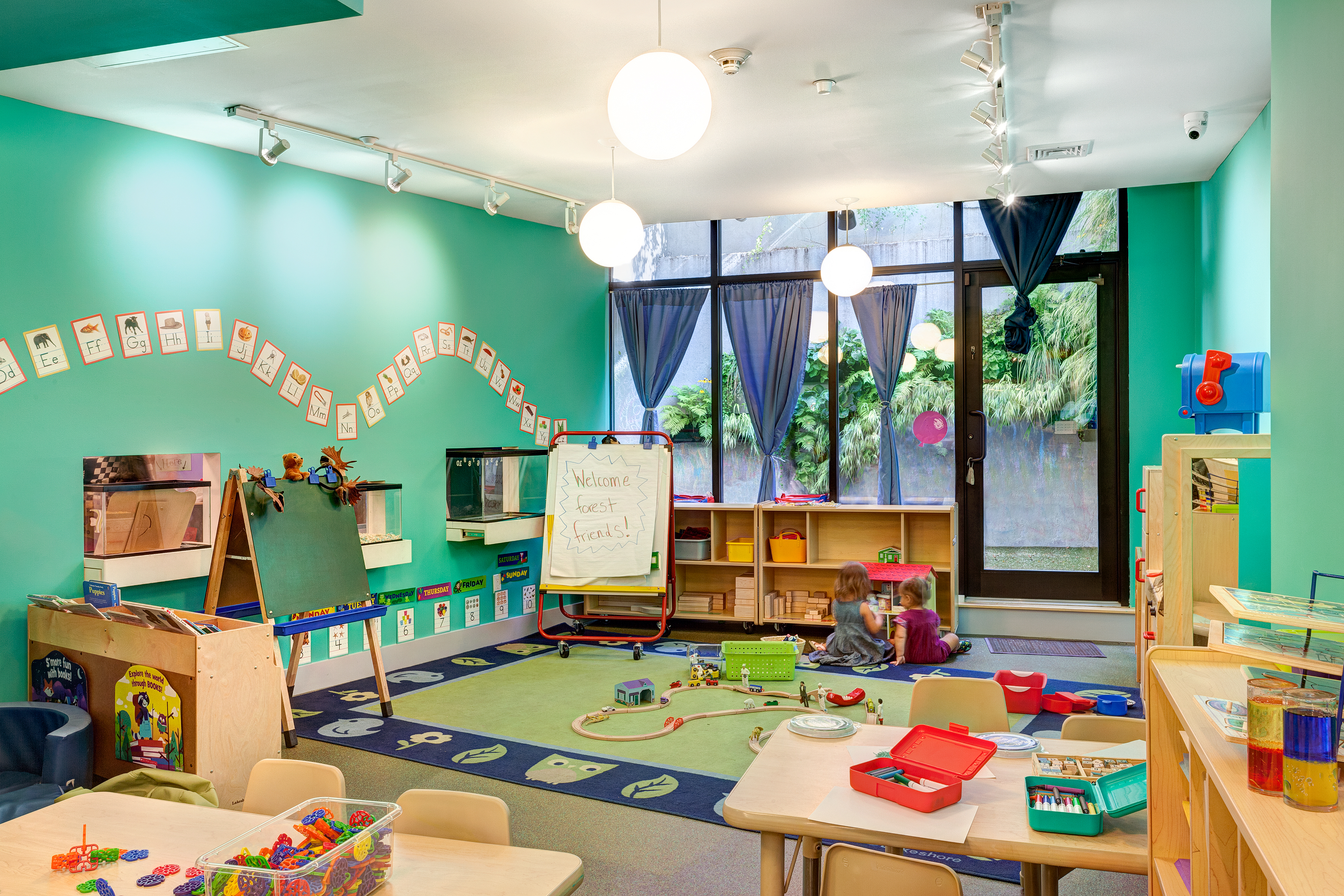 Teal-painted classroom with spherical pendant lights and a door leading to the rear yard