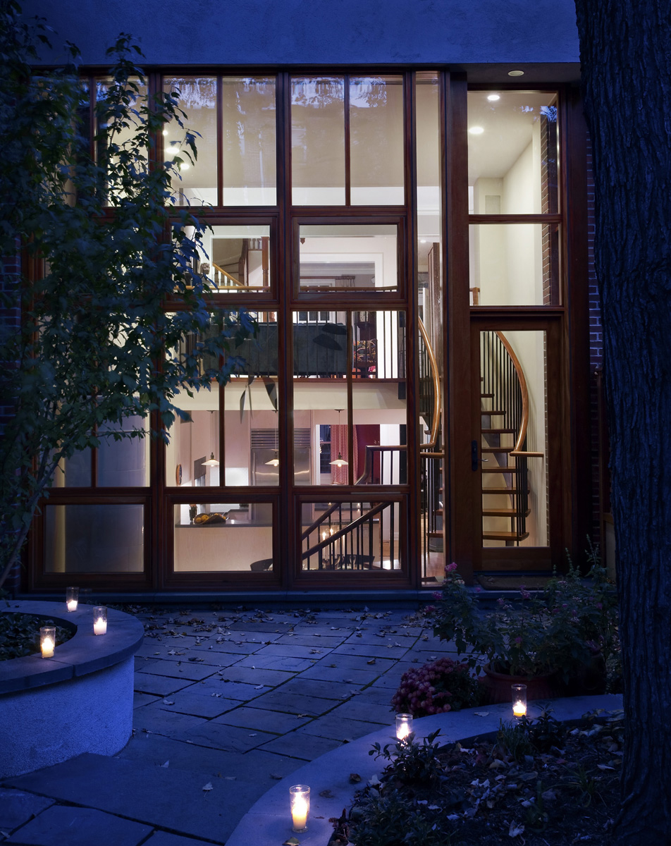 Rear façade of a Cobble Hill townhouse after our renovation with two floors of wall-to-wall glazing at twilight