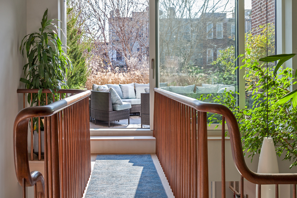 Elevated walkway above a double height space leading to an outdoor patio in a Carroll Gardens patio