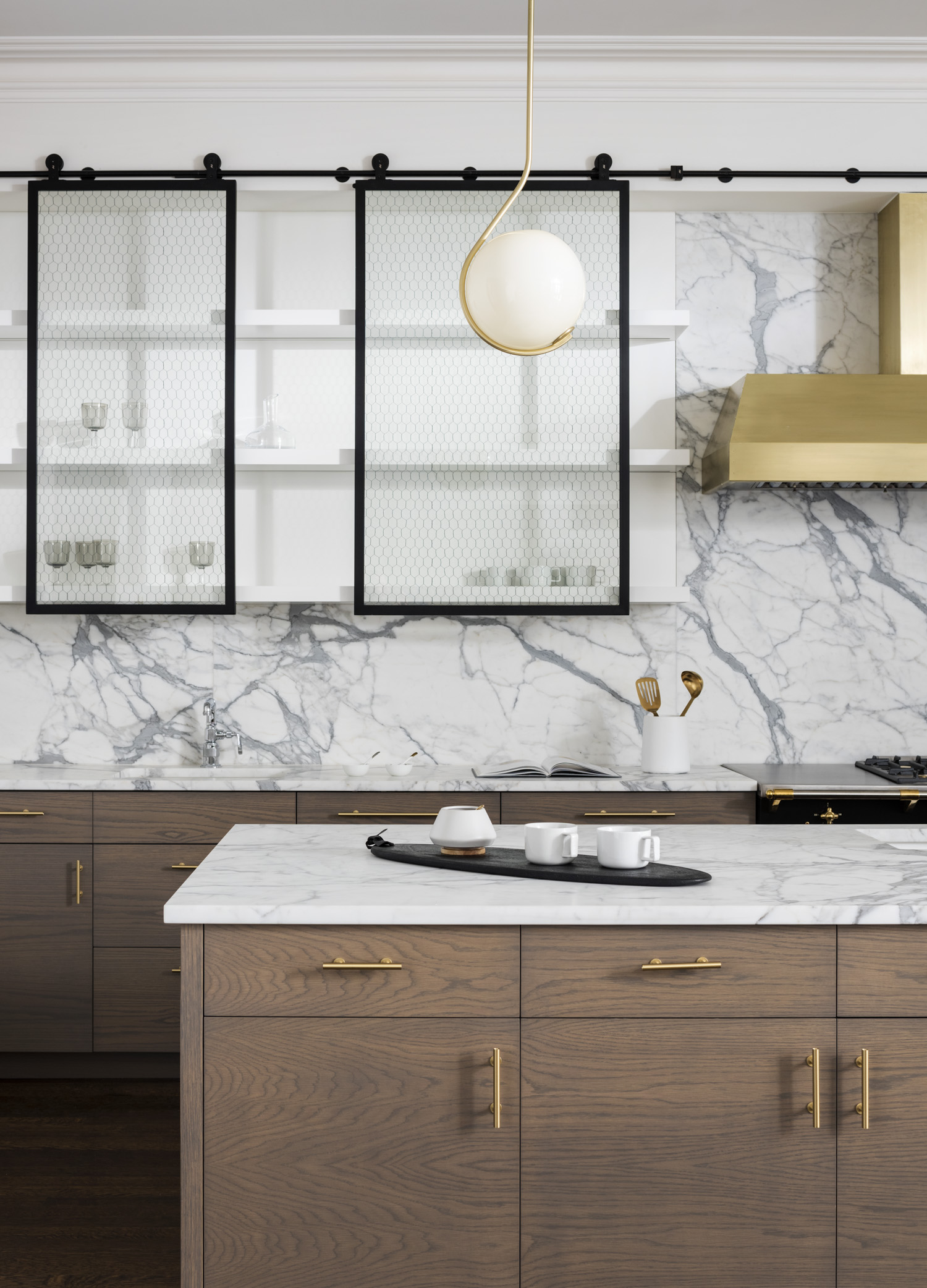 Kitchen with large marble backsplash and countertop, gold fixtures, and a custom farmhouse-style cabinetry system