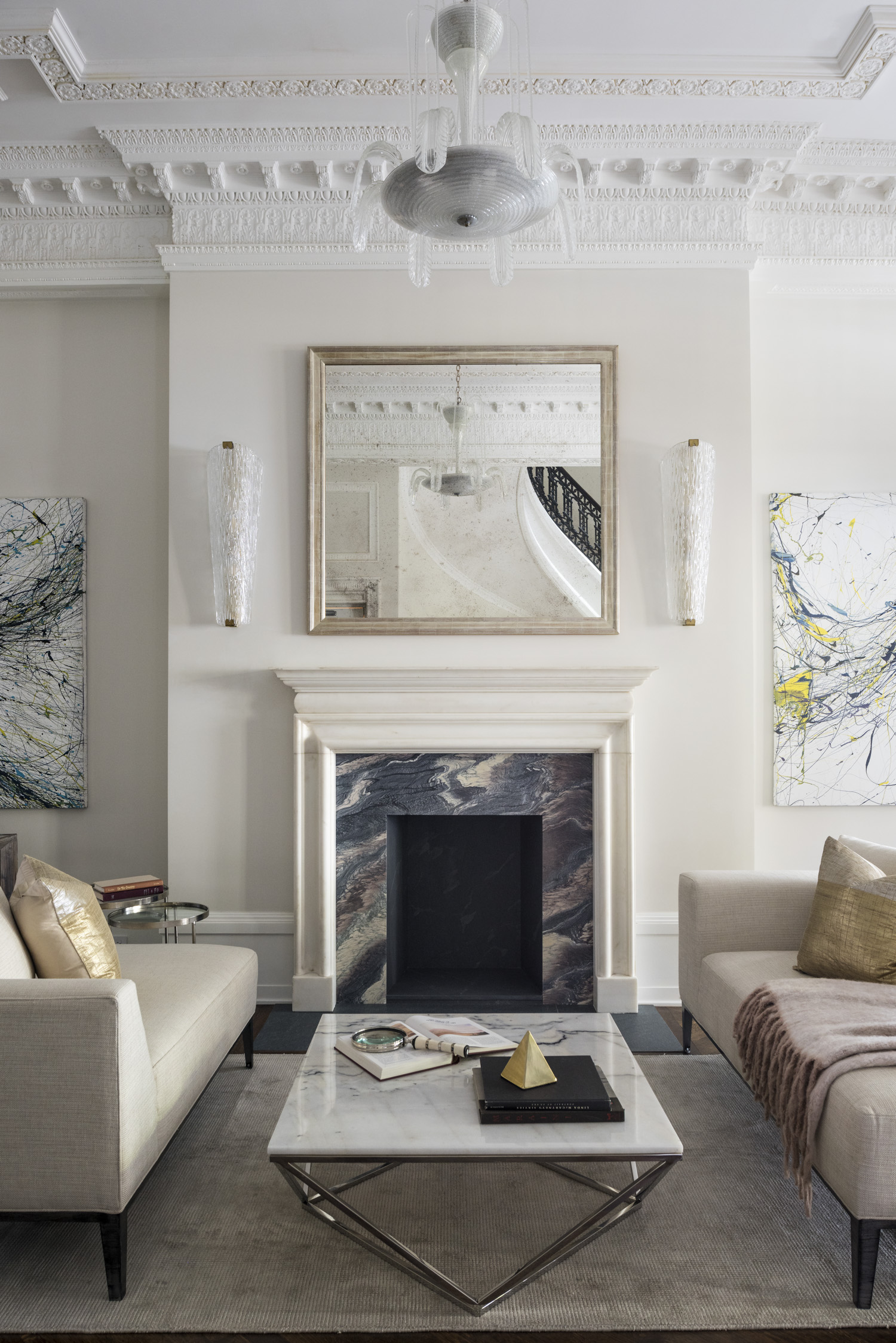 Marble fireplace with contemporary furnishings, a chandelier, and intricate crown molding details.