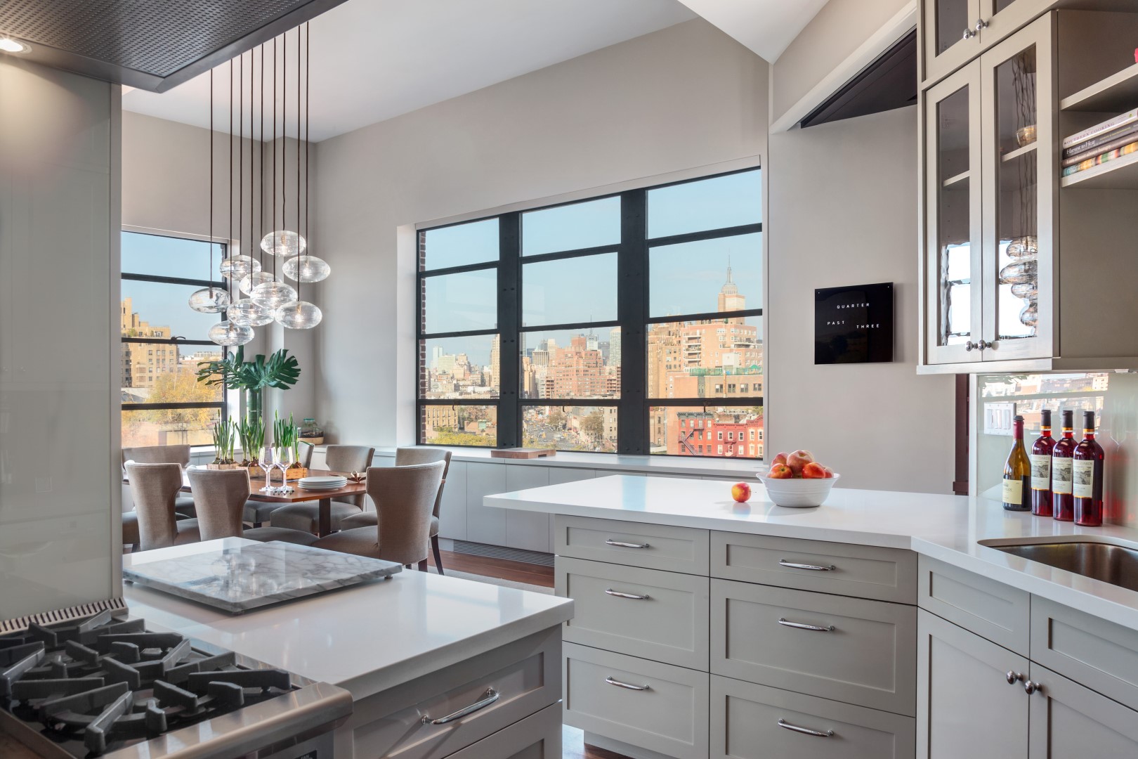 Kitchen and dining area with grey cabinetry, double hung windows, and an artful light fixture above the dining table.