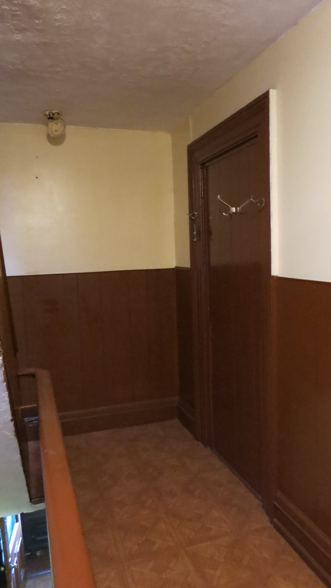 Stair hallway with dark wood paneling and door, before our renovation